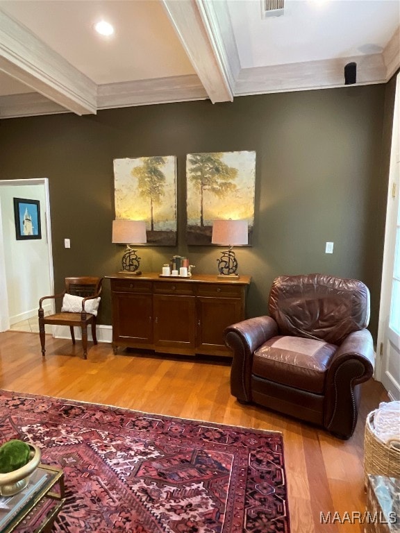 living area featuring beamed ceiling, crown molding, and light wood-type flooring