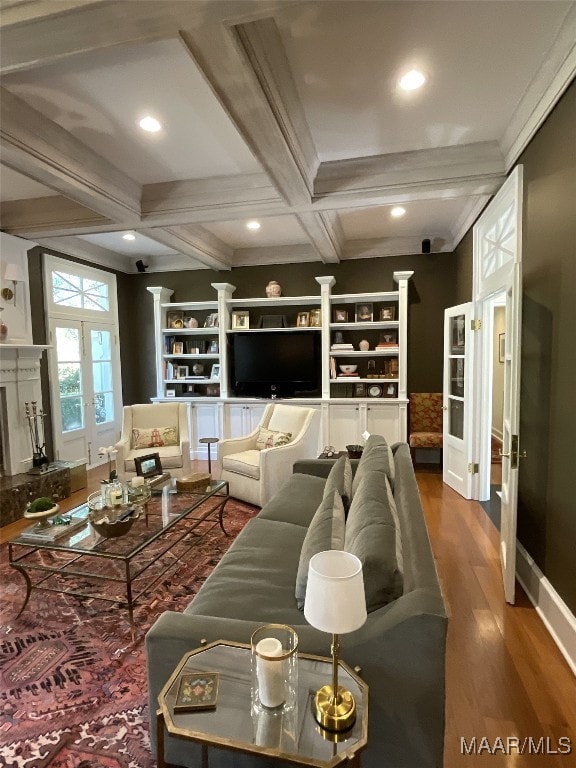 living room featuring hardwood / wood-style floors, coffered ceiling, beamed ceiling, crown molding, and a premium fireplace