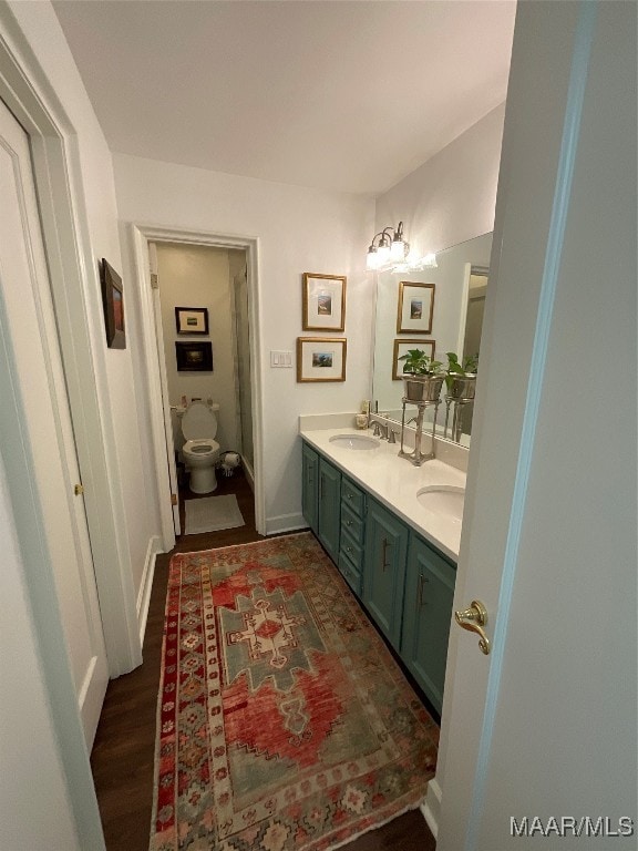 bathroom with toilet, vanity, and wood-type flooring