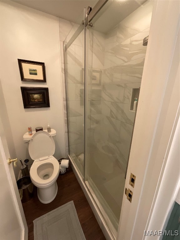 bathroom with a shower with door, hardwood / wood-style flooring, and toilet