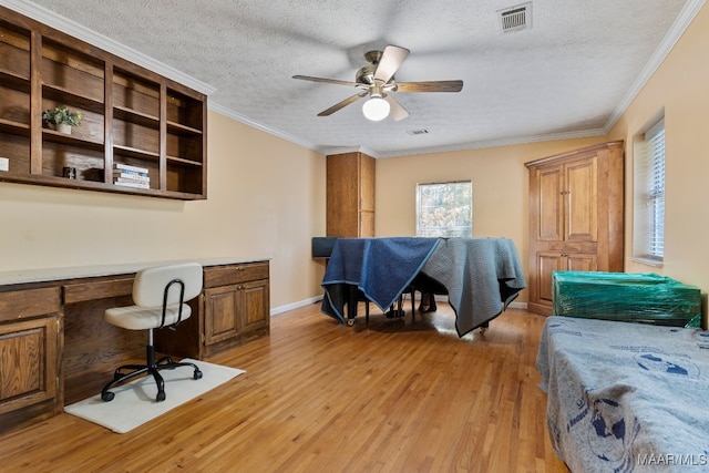 home office with built in desk, ornamental molding, a textured ceiling, and light wood-type flooring