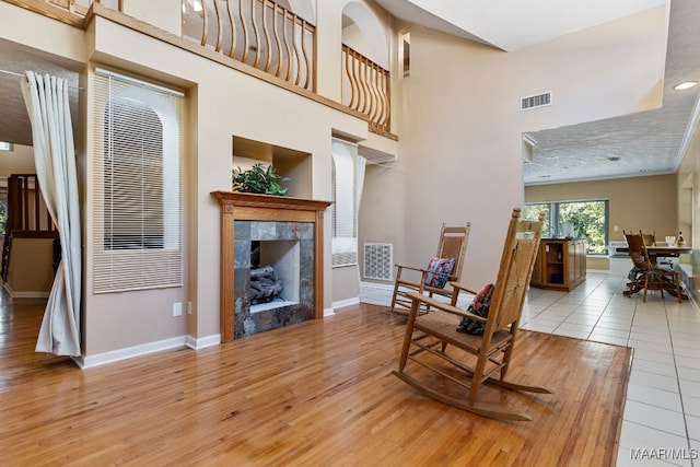 living room featuring a towering ceiling, a fireplace, and light hardwood / wood-style floors