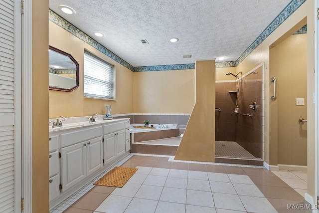 bathroom featuring vanity, tile patterned floors, a tile shower, and a textured ceiling