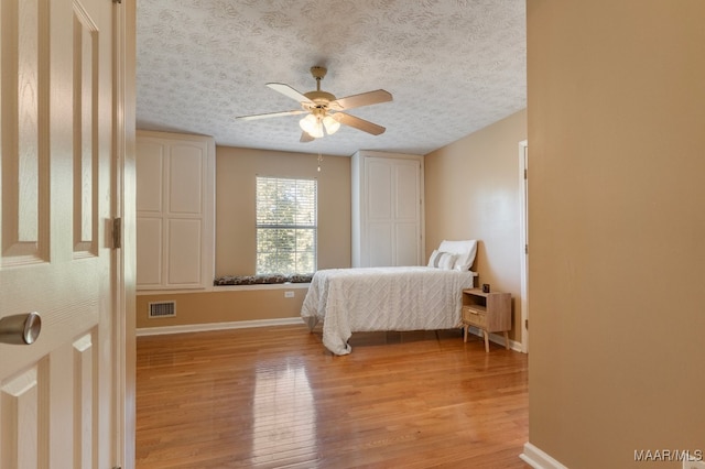 bedroom featuring a textured ceiling, light wood-type flooring, and ceiling fan