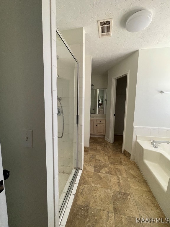 bathroom with vanity, separate shower and tub, and a textured ceiling