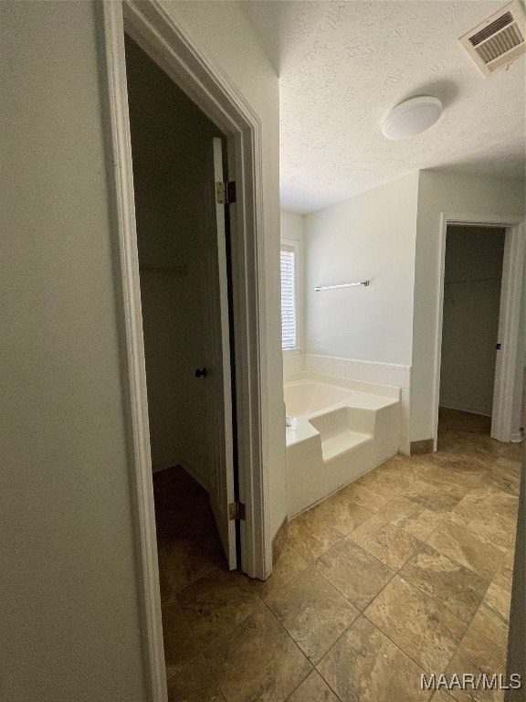 bathroom featuring a textured ceiling and a washtub