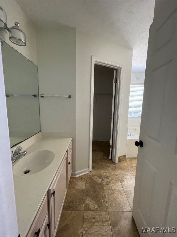 bathroom with vanity, a bathtub, and a textured ceiling