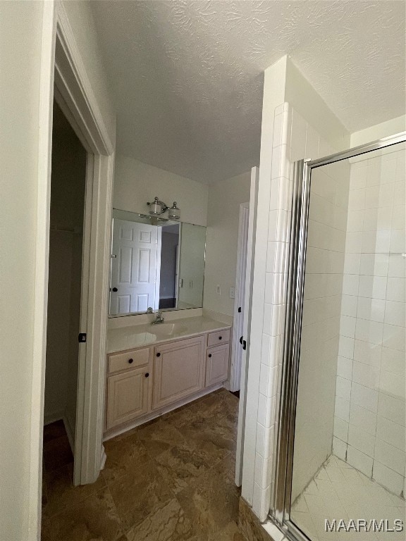 bathroom featuring vanity, an enclosed shower, and a textured ceiling