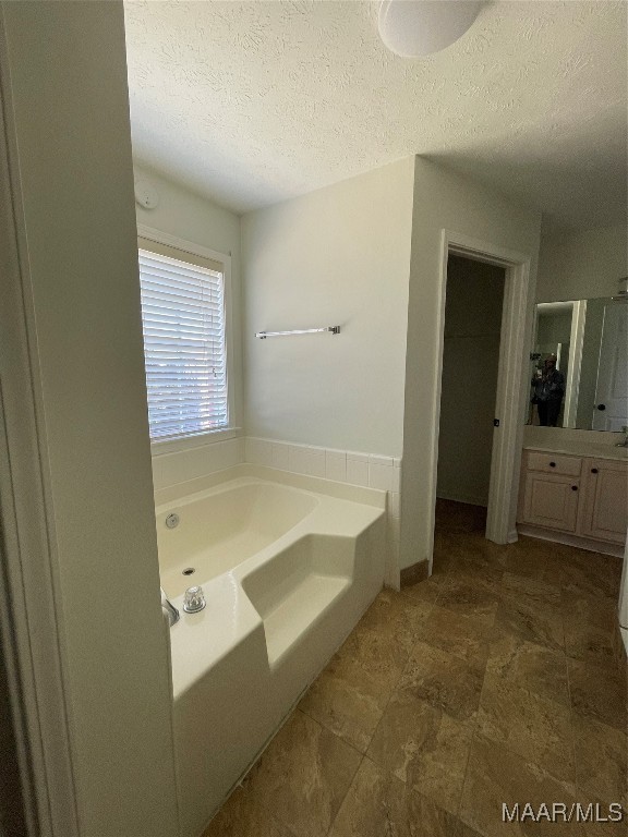 bathroom featuring vanity, a textured ceiling, and independent shower and bath