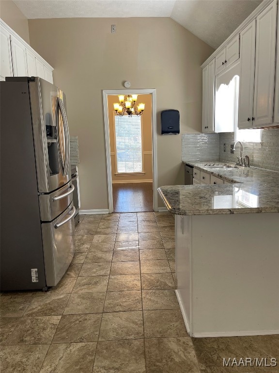 kitchen with stainless steel refrigerator with ice dispenser, kitchen peninsula, sink, vaulted ceiling, and white cabinetry