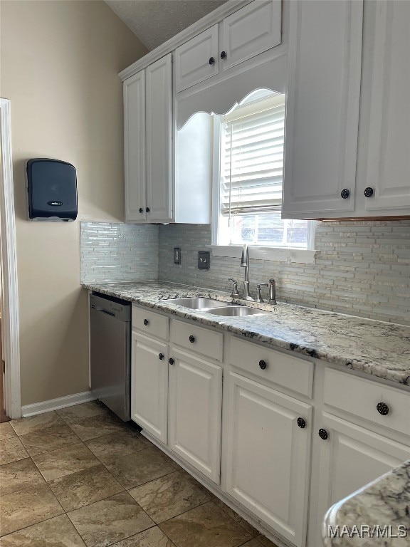 kitchen with white cabinets, tasteful backsplash, light stone countertops, dishwasher, and sink