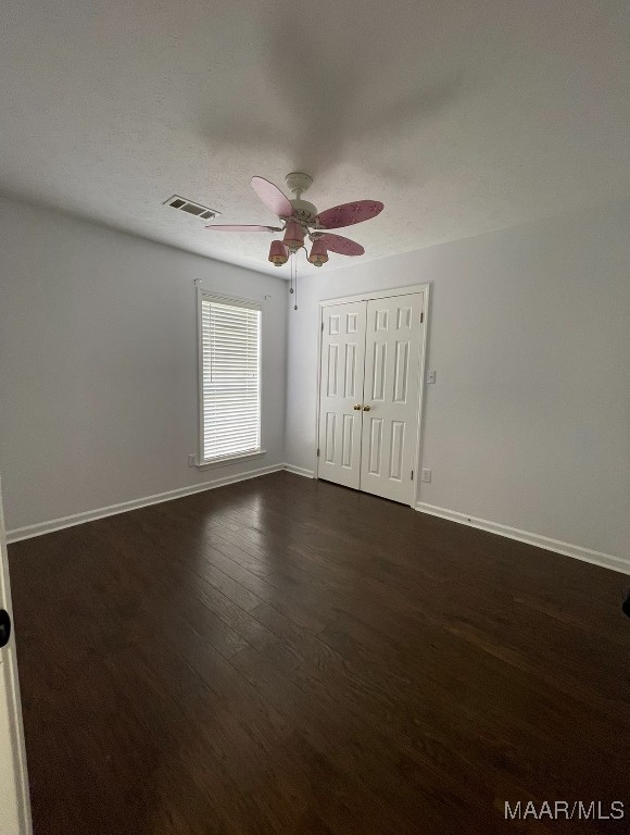 spare room with dark hardwood / wood-style floors and ceiling fan