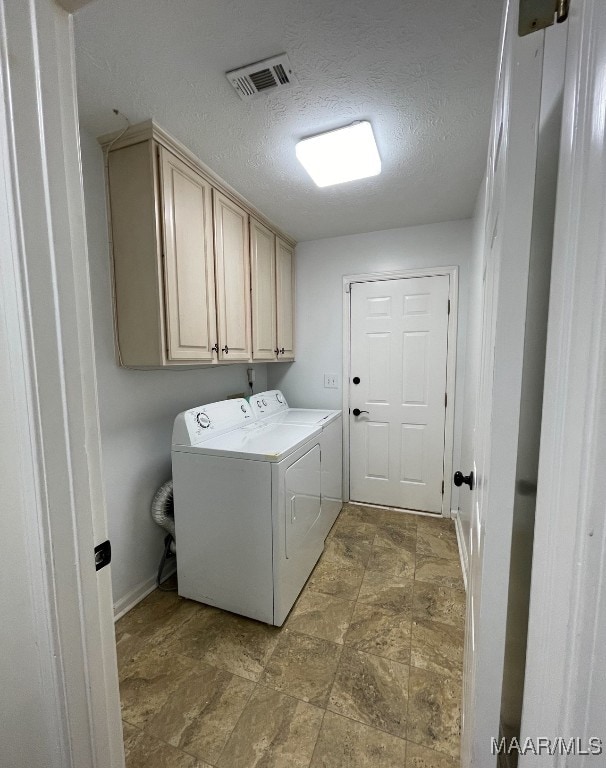 clothes washing area featuring cabinets, a textured ceiling, and separate washer and dryer