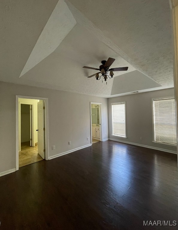 spare room featuring lofted ceiling, dark wood-type flooring, a textured ceiling, and ceiling fan