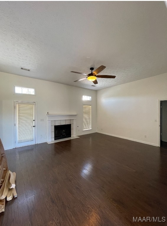 unfurnished living room with ceiling fan, a fireplace, a textured ceiling, and dark hardwood / wood-style flooring