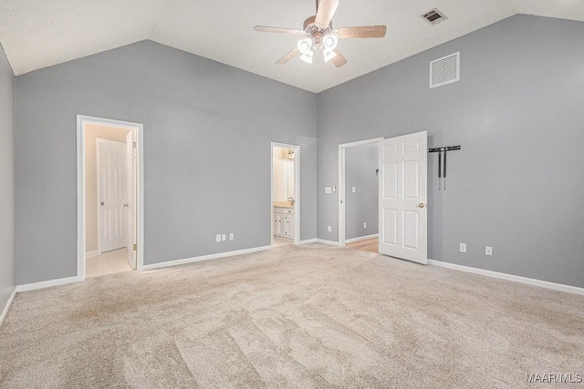 unfurnished bedroom featuring high vaulted ceiling, light colored carpet, ceiling fan, and ensuite bathroom