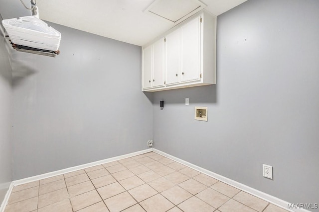 washroom with cabinets, hookup for a washing machine, and light tile patterned floors