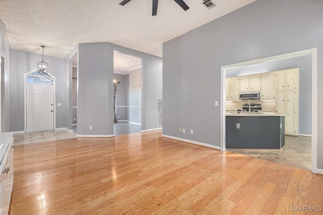 unfurnished living room with ceiling fan, lofted ceiling, and light wood-type flooring