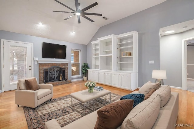 living room with a brick fireplace, lofted ceiling, ceiling fan, and light hardwood / wood-style flooring