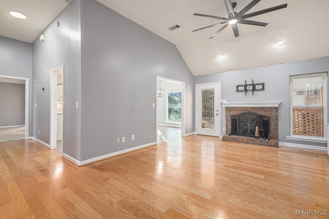 unfurnished living room featuring ceiling fan, high vaulted ceiling, a fireplace, and light hardwood / wood-style floors