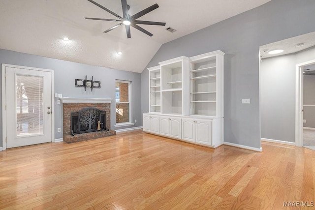 unfurnished living room featuring ceiling fan, lofted ceiling, a fireplace, and light hardwood / wood-style flooring