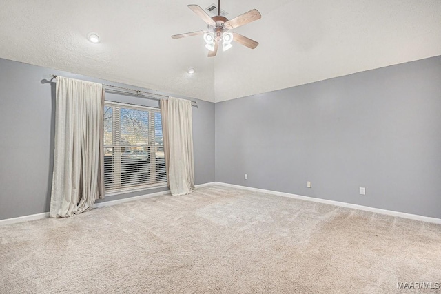 empty room with ceiling fan, lofted ceiling, carpet flooring, and a textured ceiling