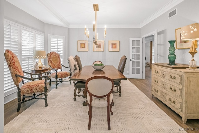 dining space featuring french doors, a notable chandelier, ornamental molding, and light hardwood / wood-style flooring