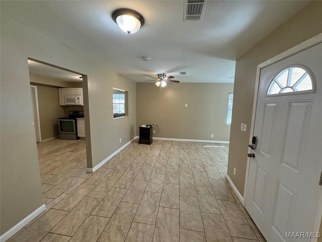foyer with ceiling fan and baseboards