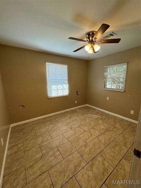 tiled spare room with healthy amount of natural light, a ceiling fan, and baseboards