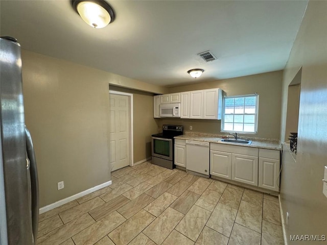 kitchen featuring appliances with stainless steel finishes, a sink, light countertops, white cabinetry, and baseboards