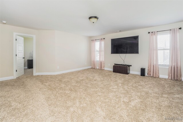 unfurnished living room with carpet flooring and plenty of natural light