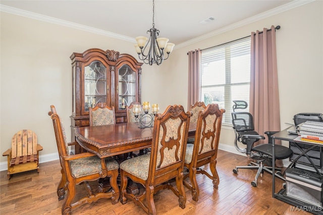 dining space featuring crown molding, wood-type flooring, and an inviting chandelier