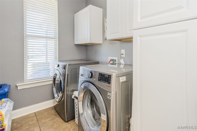 washroom with independent washer and dryer, light tile patterned floors, and cabinets