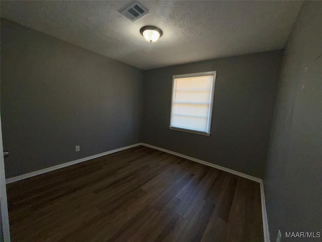 unfurnished room featuring dark wood-type flooring and a textured ceiling