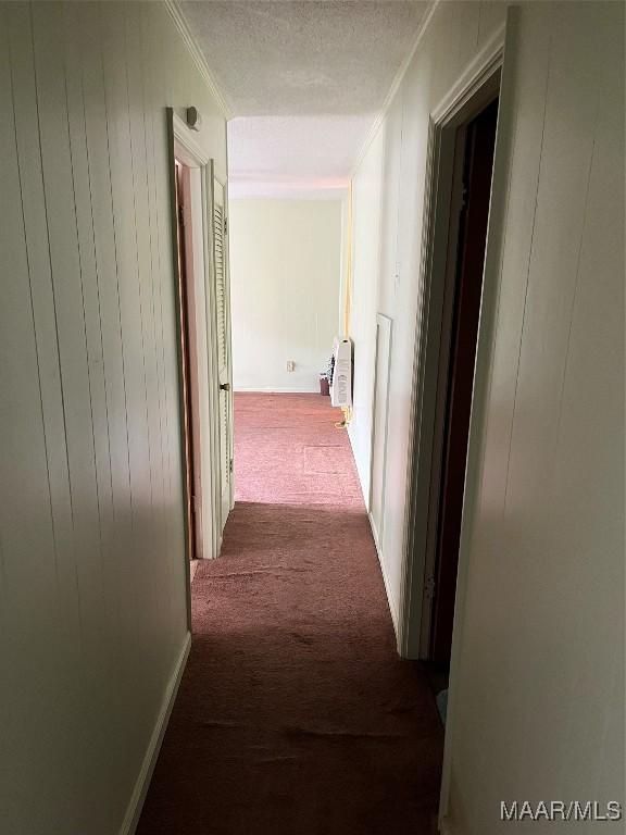 hallway featuring heating unit, light carpet, and a textured ceiling