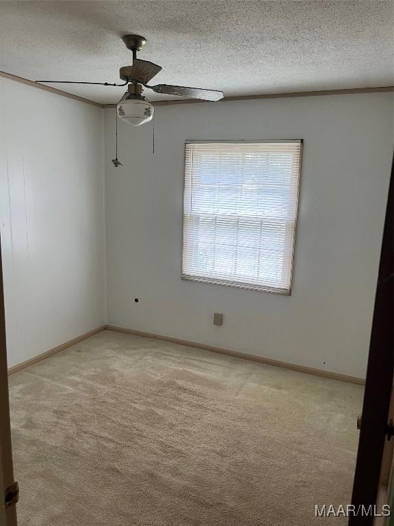 spare room featuring ceiling fan, light colored carpet, and a textured ceiling