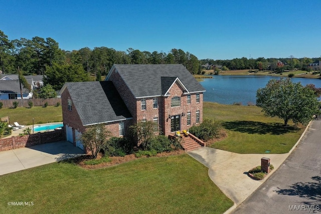 view of front of house featuring a water view, a garage, and a front lawn