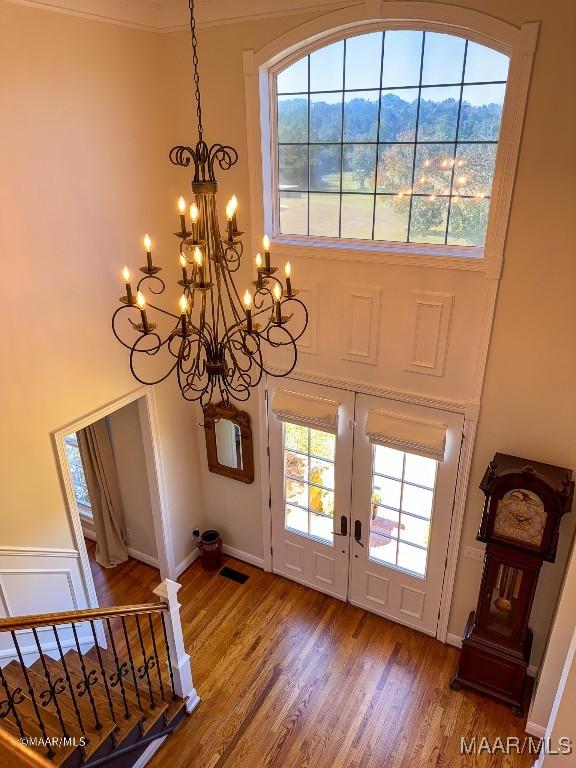 foyer entrance with wood finished floors, a notable chandelier, french doors, and a mountain view
