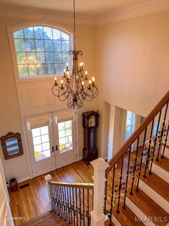 foyer entrance with a wealth of natural light, crown molding, hardwood / wood-style flooring, and a notable chandelier