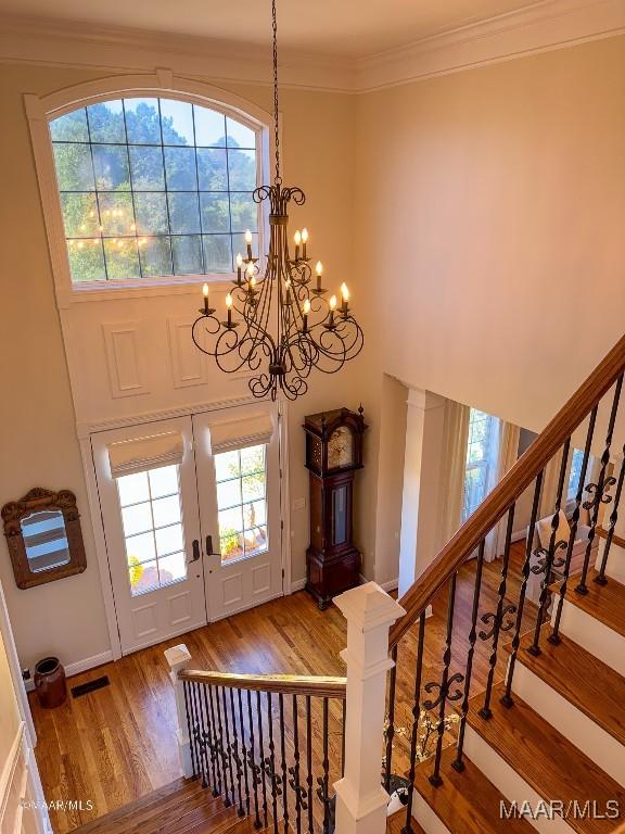 foyer entrance with stairway, a notable chandelier, visible vents, wood finished floors, and plenty of natural light
