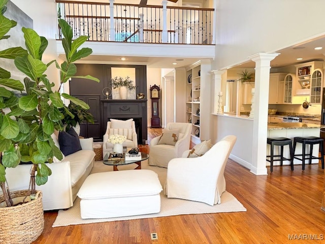 living room with baseboards, ornate columns, wood finished floors, and a towering ceiling