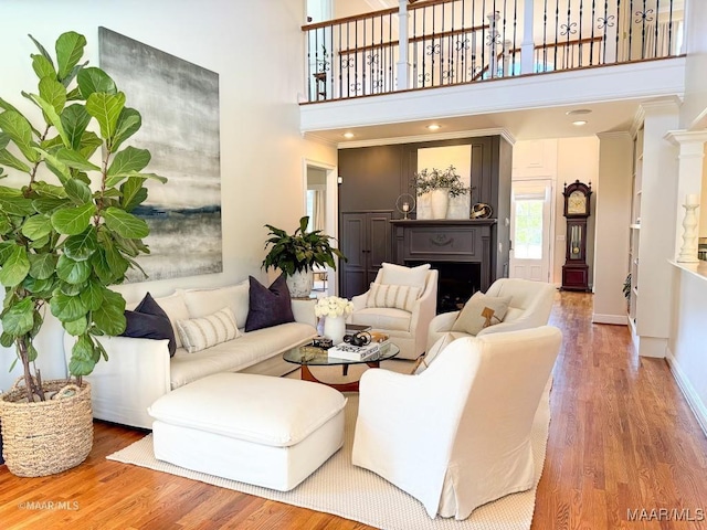 living area featuring a fireplace, a towering ceiling, wood finished floors, and baseboards