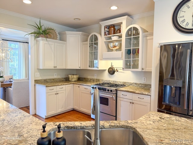 kitchen featuring appliances with stainless steel finishes, light stone counters, ornamental molding, white cabinets, and light hardwood / wood-style floors