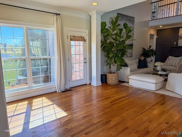 interior space with hardwood / wood-style floors, ornate columns, and crown molding