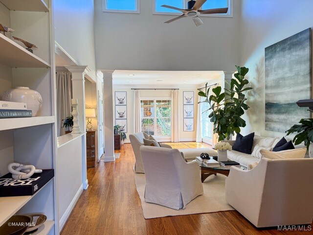 living room featuring ceiling fan, wood-type flooring, and a towering ceiling