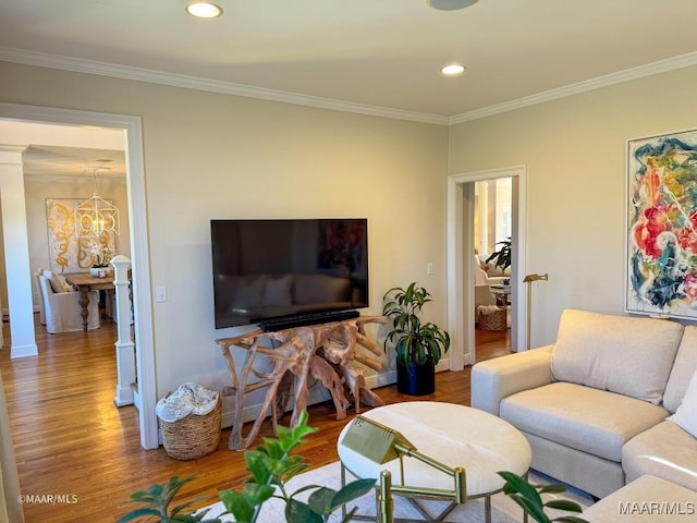 living room with recessed lighting, ornamental molding, a notable chandelier, and wood finished floors