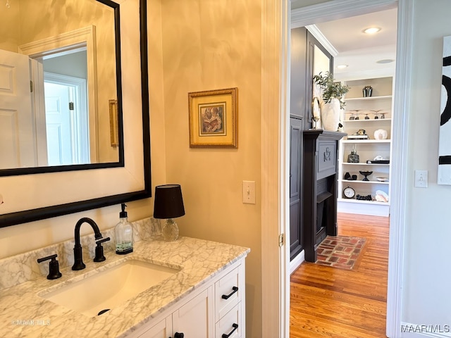 bathroom with hardwood / wood-style floors, vanity, and crown molding