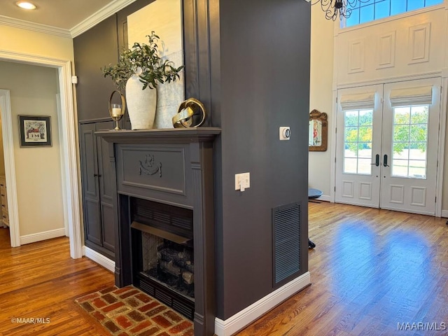 interior space with a fireplace, crown molding, visible vents, baseboards, and wood finished floors