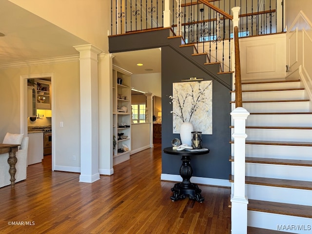 staircase with decorative columns, built in shelves, wood-type flooring, and ornamental molding