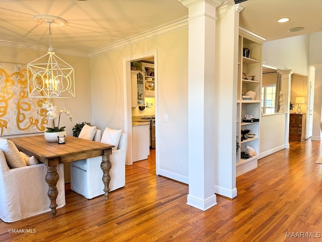 unfurnished dining area with decorative columns, ornamental molding, hardwood / wood-style flooring, built in features, and a notable chandelier